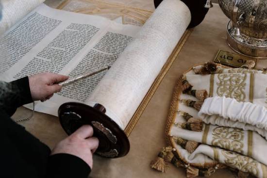 Ancient Bible Scroll with Man's Hand Pointing at it with a Metal Pointer Someone reviewing an ancient scroll represents how carefully Jewish leaders in Jesus' time studied and adhered to the law of Moses.