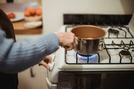 Woman putting a pot on the stove to cook with