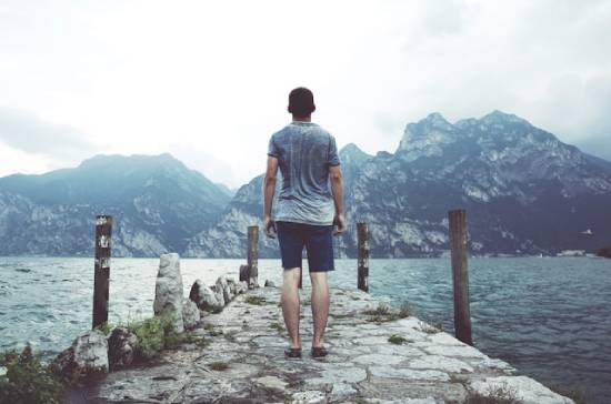 Courageous Man Standing on a Stone Platform facing the Mountains A man stands bravely on a stone pier facing the mountains. This illustrates how we can be courageous when facing spiritual warfare.