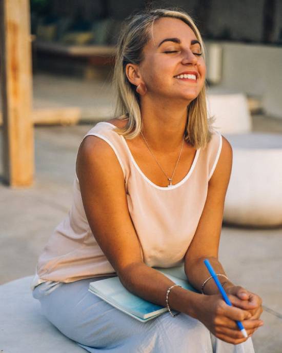 Woman smiling and journaling about her relationship with God A woman journaling while enjoying God's presence. God desires quality time with us, which is a reason why He made a day for us to rest.