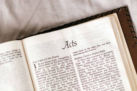 A hand holding a magnifying glass to Hebrew scrolls