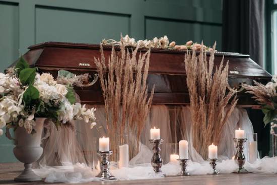 a closed casket sits in a room with flowers and candles surrounding it