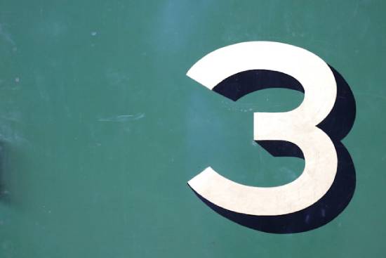 White number three on green background he number 3 in white with a blue shadow on a green background, signifying Mark's patterns of 3's
