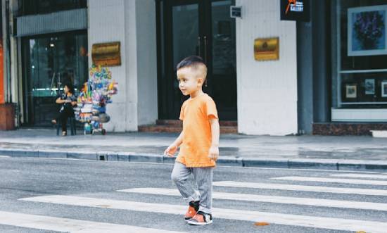 Young boy alone on the street A child crosses a crosswalk by himself, and it demonstrates how God views us as a protective dad views His children and their choices