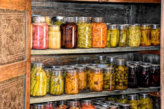 Canning jars full of preserved food on shelves Canning jars full of preserved foods fill up shelves, illustrating how country living can enable us to grow and preserve our food and reduce the need to go to the store.