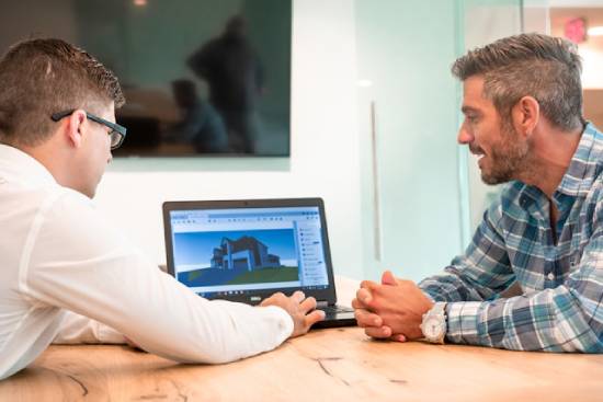 Client and salesman discussing home building plans for the country A real estate agent and his client go over building plans for a rural home.