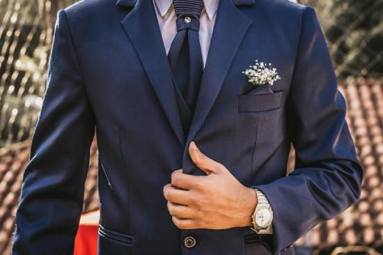 A groom in a dark blue suit stands waiting for his bride.