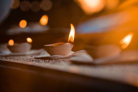 Three small oil lamps burn on a ledge at night.