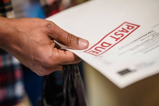 Man holding a bill with a Past A person holds a Past Due notice in their hand