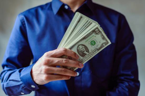 Rich man holding a lot of money A man holds a spread of cash in his hand.