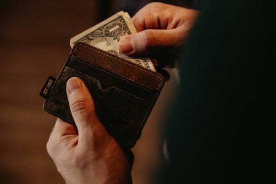 Someone taking money out of their wallet A person pulls cash out of their wallet.