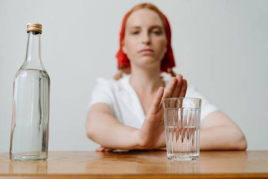 Woman pushing away alcohol and resisting temptation A woman holding up her hand to refuse a glass of alcohol