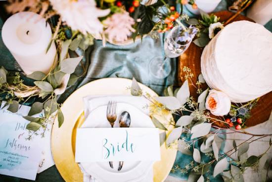 Decorated table setting with a nametag that says "Bride" An overhead shot of the bride's seat at a decorated table, complete with candles, flowers, fancy silverware, and an empty champagne glass